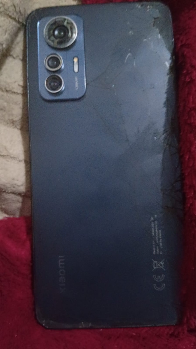 Traseira do Xiaomi 12 azul sobre tecido vermelho, ilha de três câmeras e vidro riscados